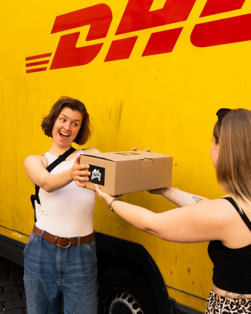 Deux femmes se passent un colis Kailar devant une camionnette de livraison jaune